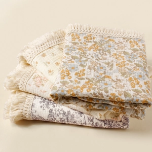 Detail of sunflower print baby blanket featuring delicate cream fringe and cotton gauze texture