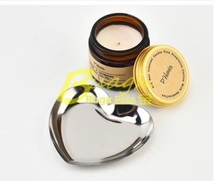 Close-up of heart-shaped stainless steel tray holding a scented candle on a smooth surface