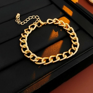 Close-up of golden Cuban chain bracelet with lobster clasp and adjustable extension on black leather