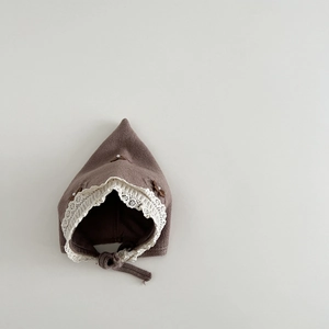 Detailed macro view of baby knit bonnet with white lace trim, bow and pearl accents