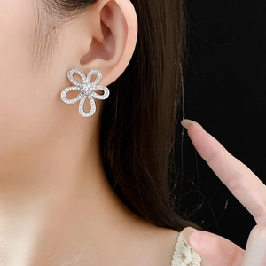 Gros plan de boucles d'oreilles fleur évidée en argent avec zircone sur l'oreille