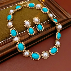Detail of vintage jewelry set with turquoise gems and white pearls on green velvet
