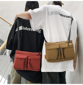 Rear view of couple wearing brick red and khaki nylon messenger bags in utility style