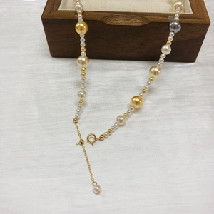 Detail of multi-colored Akoya pearls with gold clasp on wooden jewelry box