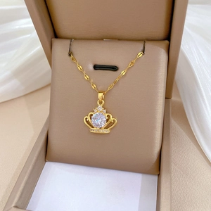 Detail shot of a hollow gold crown pendant with sparkling crystals in a beige jewelry box