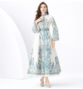 Detail of a white mandarin collar dress featuring blue paisley prints and lace trims