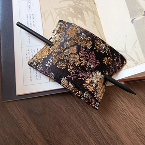 Detail of embroidered floral fabric hair bun cover with black vintage hairpin