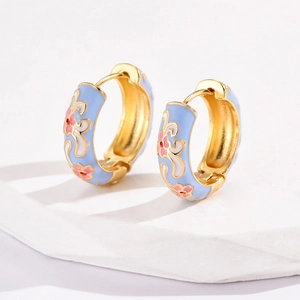 Macro detail of sky blue enamel flower earrings with pink petals on white stone base