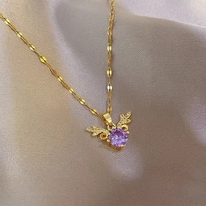 Macro view of gold chain necklace with purple gemstone pendant and zircon angel wings