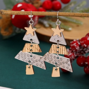 Detail of layered Christmas tree earrings with gold stars hanging on festive pine branches