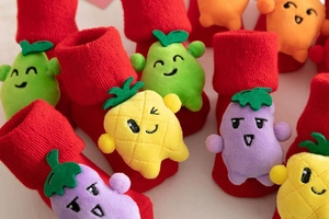 Close-up of red Christmas baby socks with 3D plush fruit dolls and knit texture