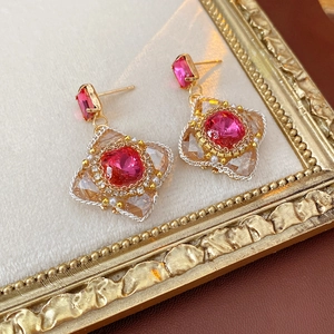 Detail of vintage gold floral earrings with pink center stone and pearls on velvet