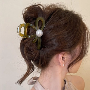 Elegant dark green bow hair claw clip with large pearl on model bun hairstyle