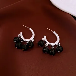 Vintage C-shaped silver earrings with glossy black bead pendants on dark satin fabric