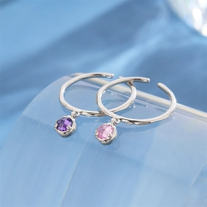 Detail of adjustable S925 silver rings with colorful zircon pendants on silk background