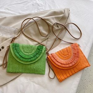 Detail of woven raffia envelope bags in bright green and orange with fringe textures