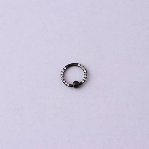 Détail du piercing fer à cheval noir avec zircons blancs et perle noire sur fond violet