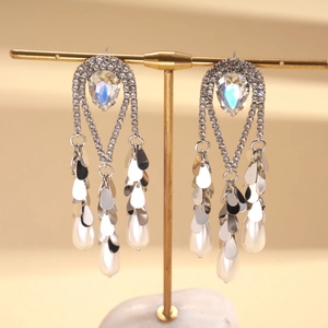 Détail de boucles d'oreilles dorées 18k avec pampilles de perles et cristaux brillants