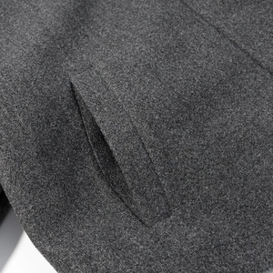 Macro detail of dark grey wool blend fabric showing fiber texture and side pocket stitching