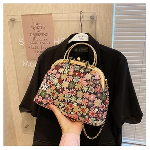 Macro detail of retro floral embroidery and golden metal frame on a stylish handbag