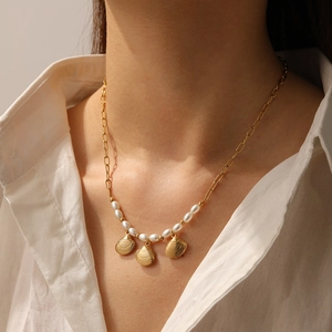 Détail du collier à pendentif coquillage doré avec perles porté par un mannequin