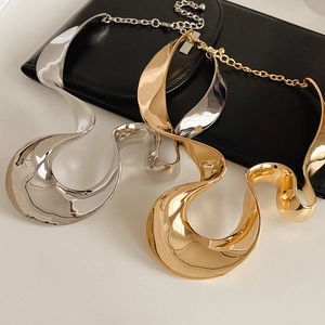 Chunky gold and silver irregular wave pendant necklaces shown on white background