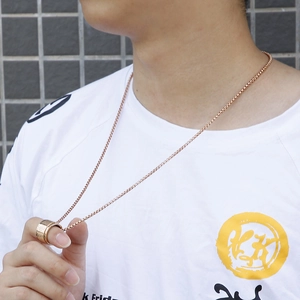 Detailed view of rose gold spinning mantra pendant necklace worn on a casual white t-shirt