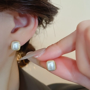 Gros plan de boucles d'oreilles perles carrées avec bordure dorée brillante