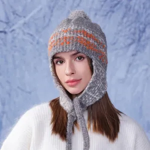 Winter knit earflap hat with colorful geometric patterns and a faux fur pom pom