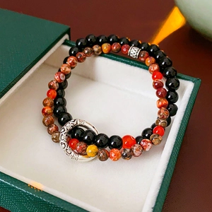 Detailed view of a double-layer bead bracelet with vintage silver charms in a green box