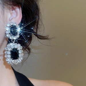 Makroaufnahme von glitzernden Silberohrringen mit schwarzen Steinen am Modellohr