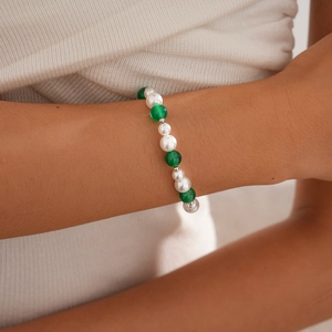 Close-up of a three-piece beaded bracelet with white pearls and green agate on a wrist