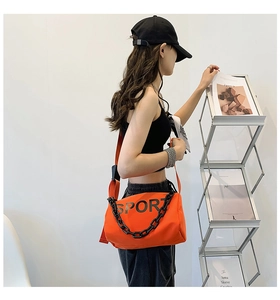 Détail du sac à bandoulière en nylon orange avec imprimé SPORT et chaîne sur mannequin