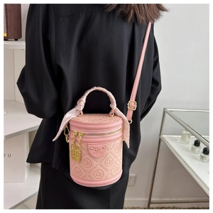 Detailed view of pink cylinder bucket bag with silk handle and gold metal hardware