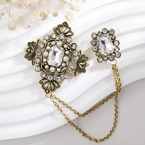Detail of vintage gold brooch with sparkling crystals, pearls and double hanging chains