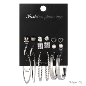 Close-up of 9-pair earring set with pearls, hearts, and hoops on a black display card