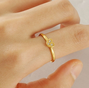 Detailed view of 18K gold heart ring with three sparkling diamonds on finger