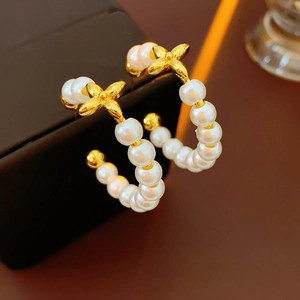 Close-up of 18K gold plated hoop earrings with pearls and a four-leaf clover detail