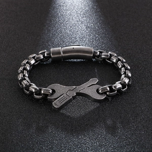 Detail of vintage silver link chain bracelet featuring wrench and screwdriver cross pendant