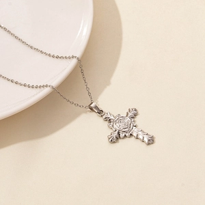 Macro detail of the silver cross pendant featuring an intricate rose flower design