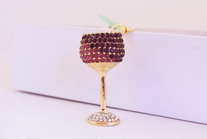 Detailed view of wine glass earring with purple rhinestones on a white box