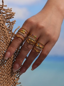 Detail of 18k gold plated multi-piece ring set with zircons and colorful enamel in sunlight
