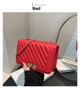 Detail of red quilted shoulder bag with golden chain strap and rectangular twist lock