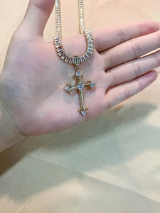 Detailed macro view of a luxury gold-tone cross pendant with sparkling zircon inlays