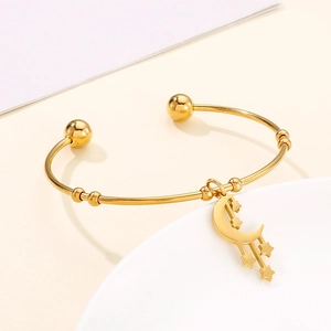 Detail of gold moon and star pendant charms on an open stainless steel bracelet