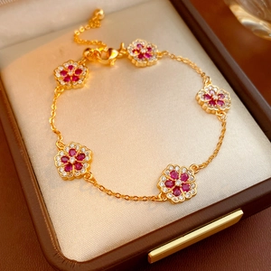 Detail of flower bracelet with red stones and zircon pavé on warm jewelry box