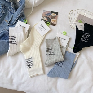 Mid-calf cotton socks in neutral tones with minimalist lettering and tag packaging