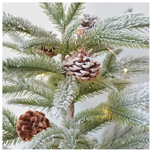 Detail of frosted pine branches with natural cones and warm white LED string lights