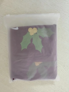 Folded purple PVC Christmas ball in frosted packaging on a light wood background