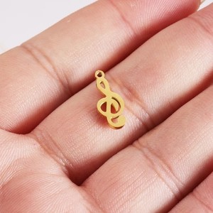 Compact golden musical note pendant in mirror polished stainless steel held in hand